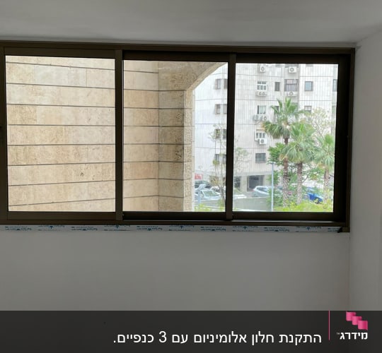 חלון אלומיניום עם מסגרת חומה על קיר לבן